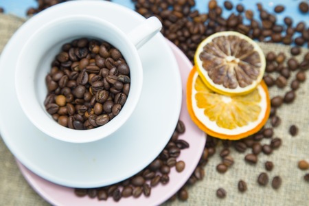 Love Coffee Concept. A white cup and saucers with coffee beans and orange slices on a burlap fabric, top viewの写真素材