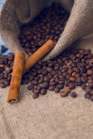 Love Coffee Concept. Coffee beans pouring from a burlap sack and cinnamon sticks, close upの写真素材