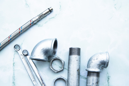 Various plumbers tools and plumbing materials including stainless steel pipe, elbow joint, wrench...