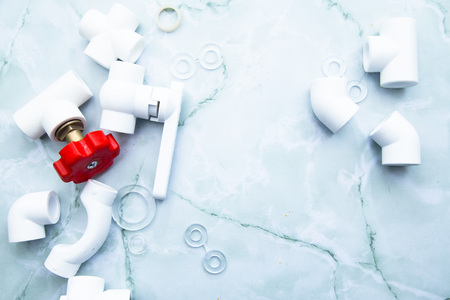 Various plumbers tools and plumbing materials including plastic PVC pipe, elbow joint, wrench and spanner. Bright white background. Top view, copyspaceの写真素材
