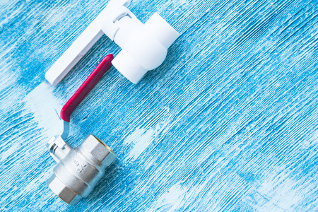 Various plumbers tools and plumbing materials including stainless steel pipe, elbow joint, wrench and spanner. Blue wooden background. Top view, copyspaceの写真素材