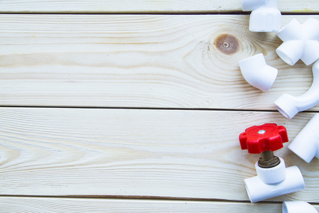 Various plumbers tools and plumbing materials including plastic PVC pipe, elbow joint, wrench and spanner. White wooden background. Top view, copyspaceの写真素材
