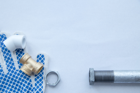 Various plumbers tools and plumbing materials including stainless steel, plastic and copper pipe, elbow joint, wrench and spanner. White background. Top view, copyspaceの写真素材