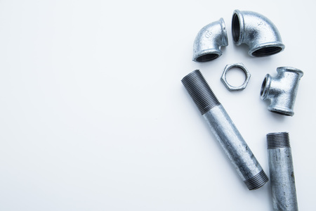 Various plumbers tools and plumbing materials including stainless steel pipe, elbow joint, wrench and spanner. White background. Top view, copyspaceの写真素材