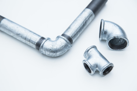 Various plumbers tools and plumbing materials including stainless steel pipe, elbow joint, wrench and spanner. White background. Top view, copyspaceの写真素材