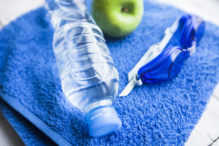 Time for diet slimming weight loss concept. Sport fit fitness, towel, swimming glasses and water on...