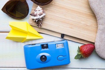 Preparing for vacation, travel or journey. Travel planning. Booking hotel. White wooden background with sunglasses, headphones, seashells and strawberry.の写真素材