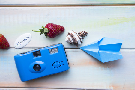 Preparing for vacation, travel or journey. Travel planning. Booking hotel. White wooden background with sunglasses, headphones, seashells and strawberry.の写真素材