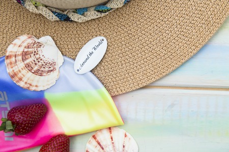Preparing for vacation, travel or journey. Travel planning. Booking hotel. White wooden background with sunglasses, hat, seashells and strawberryの写真素材