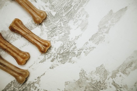 Dry pet food chewing bones on white stone background top view copyspace