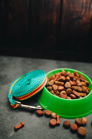 Dry pet food in bowl and a leash on dark stone background top view copyspaceの写真素材