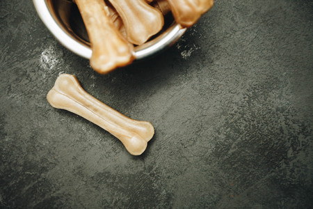 Dry pet food chewing bones in a bowl on dark stone background top view copyspaceの写真素材