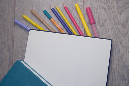 Notepad with pencils and colorfull markers on wood board background. Education or business photo. Take note of the product for book with paper and concept or copy space.の写真素材