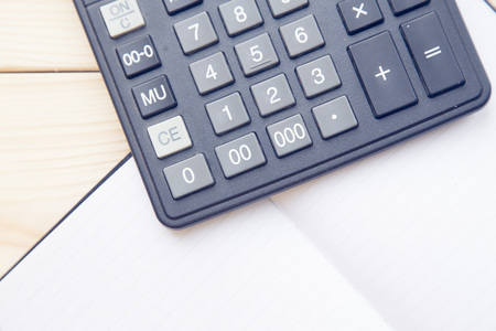 Notepad and calculator on wood board background. Education or business photo. Take note of the...