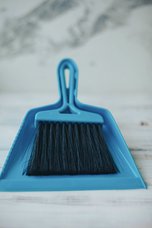 Cleaning house or office concept. A blue plastic scoop with a broom on white stone background, close upの写真素材