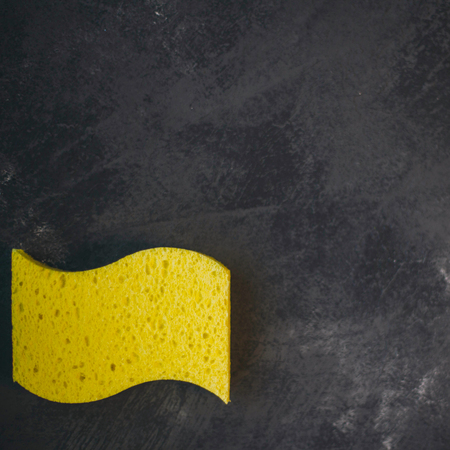 Cleaning house or office concept. Dark stone background with a yellow sponge ,top view, flat layの写真素材