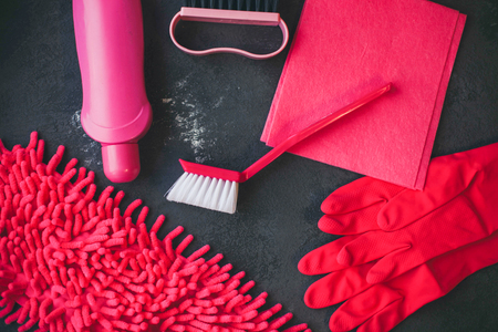 Cleaning house or office concept. A set of pink cleaning supplies on a dark concrete background, top view, flat layの写真素材