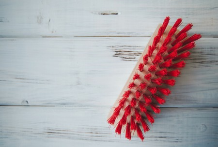 Cleaning house or office concept. Wooden clothes brush with red bristles on a white wooden table, close up, top viewの写真素材
