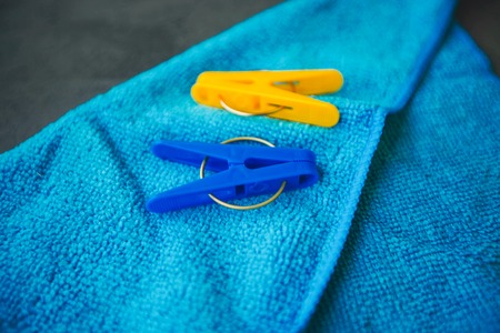 Cleaning house or office concept. A bluecleaning rag and clothes pegs on a dark concrete background, top view, close upの写真素材