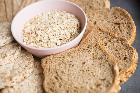 Healthy Breakfast, Sport, Fitness, Weight Loss, Diet Concept. A bowl of oat flakes, wholegrain bread, crisps and tape-measure, dark stone backgroundの写真素材