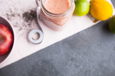 Healthy Breakfast, Sport, Fitness, Weight Loss, Diet Concept. A glass of smoothie, fresh fruit and tape-measure on a napkin ,dark stone background, top viewの写真素材