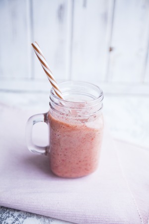 Healthy Breakfast, Sport, Fitness, Weight Loss, Diet Concept. A glass of fruit smoothie with a straw on a napkin ,white wooden and stone background, close upの写真素材