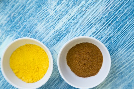 Dry spices and herbs in ceramic cups on a light blue wooden background with copy space, top view,...