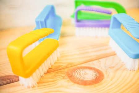 Cleaning house or office concept. Colorful plastic brushes against a natural wooden background,...