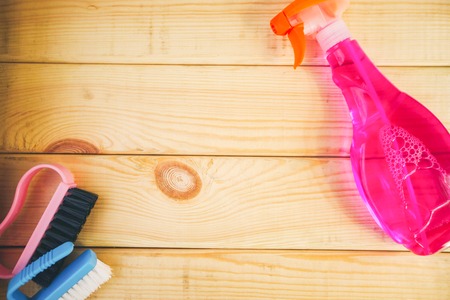 Cleaning house or office concept. Colorful plastic brushes and a bottle of pink liquid detergent with sprayer on a natural wooden background, top view, flat layの写真素材