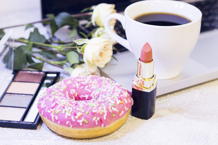 Make Up Beauty Fashion Business Concept. Nude soft colors lipstick and eyeshadow palette, cup of coffee, donut and white roses on a white stone background with laptop, close upの写真素材