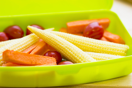 Healthy Lunch Concept. baby corns, cherry tomatoes, carroots in a green lunch box, close upの写真素材