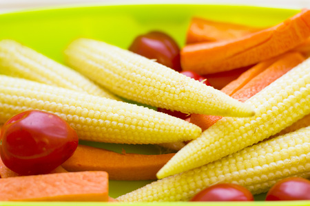 Healthy Lunch Concept. baby corns, cherry tomatoes, carroots in a green lunch box, close upの写真素材