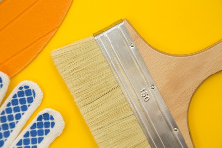 Repair and renovation concept. A set of tools for repair with brushes, screwdriver, gloves on a yellow background top view, flat lay, copy spaceの写真素材