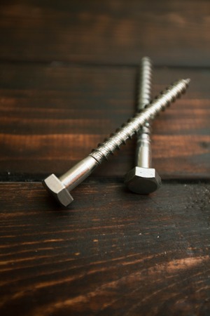 Repair modern tools: screws on dark wooden background, top view, copy spaceの写真素材