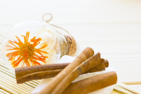 Spa and wellness setting with yellow flower, green candle, oil, cinnamon and soap on wooden white...