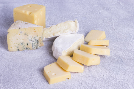 Cheese cuts with figs, nuts, honey, grapes on a dark rustic wooden boards background. Top view