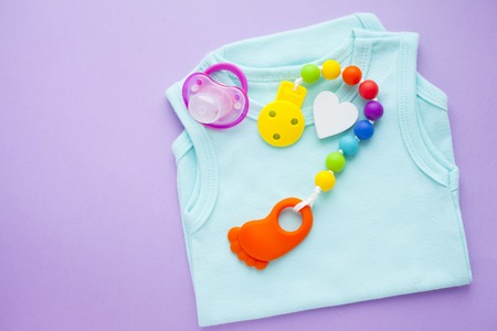Baby yellow booties. Children's shoes and toys on purple background. Newborn. Top viewの写真素材