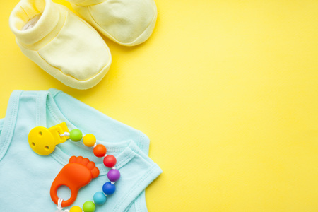 Baby yellow booties. Children's shoes and toys on yellow background. Newborn. Top view