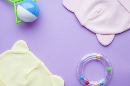 Baby yellow booties. Children's shoes and toys on purple background. Newborn. Top viewの写真素材