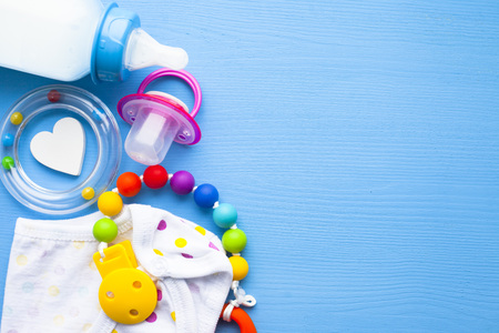 Baby yellow booties. Children's shoes and toys on blue background. Newborn. Top view
