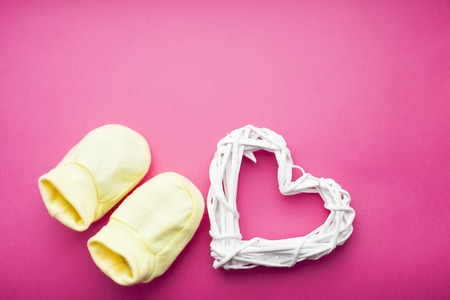 Baby yellow booties. Children's shoes and toys on pink background. Newborn. Top viewの写真素材