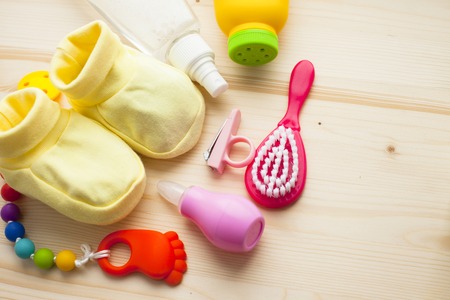 Baby yellow booties. Children's shoes and toys on white wooden boards background. Newborn. Top viewの写真素材