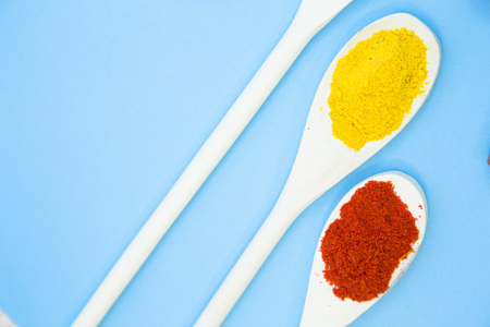 Cooking Hot Spicy Food Concept. Dry spices and herbs in wooden spoons, light blue background, close...
