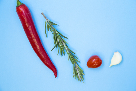 Cooking Hot Spicy Food Concept. Chili pepper, rosemary and cherry tomatoe light blue background, close up, top viewの写真素材