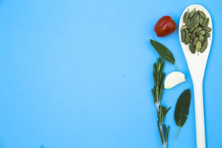 Cooking Hot Spicy Food Concept. Dry beans in wooden spoon and fresh herbs cherry tomatoes on a light blue backhround, top view, copy spaceの写真素材