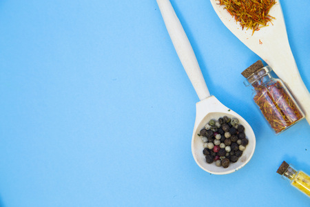 Cooking Hot Spicy Food Concept. Dry spices in wooden spoon and glass jars with cork on a light blue backhround, top view, copy spaceの写真素材