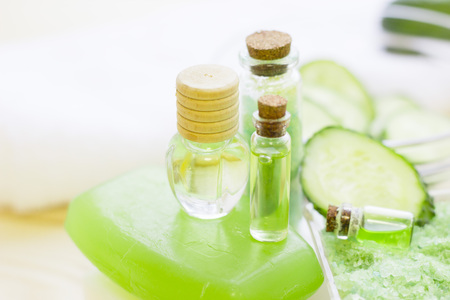 Cucumber home spa and hair care concept. Sliced cucumber, bottles of oil, soap, jar of mask, bathroom towel. White board background. Closeupの写真素材