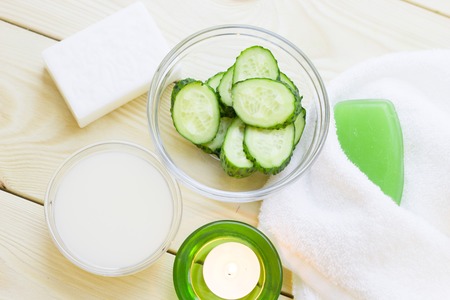 Cucumber home spa and hair care concept. Sliced cucumber, bottles of oil, soap, jar of mask, bathroom towel. White board background. Closeupの写真素材