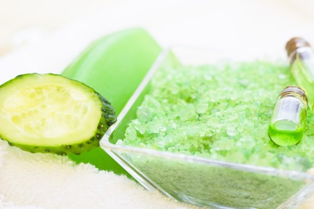 Cucumber home spa and hair care concept. Sliced cucumber, bottles of oil, sea salt, bathroom towel. White board background. Closeupの写真素材