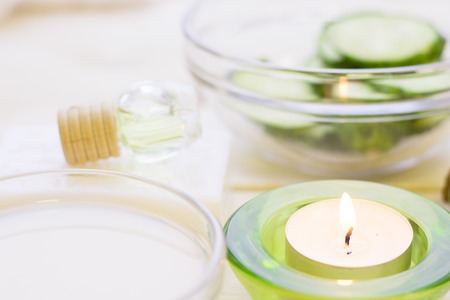 Cucumber home spa and hair care concept. Sliced cucumber, bottles of oil, jar of mask and a tealight.の写真素材